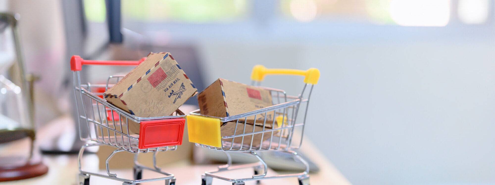 Mini caddie de supermarché contenant des paquets sur un bureau, symbolisant les achats en ligne.