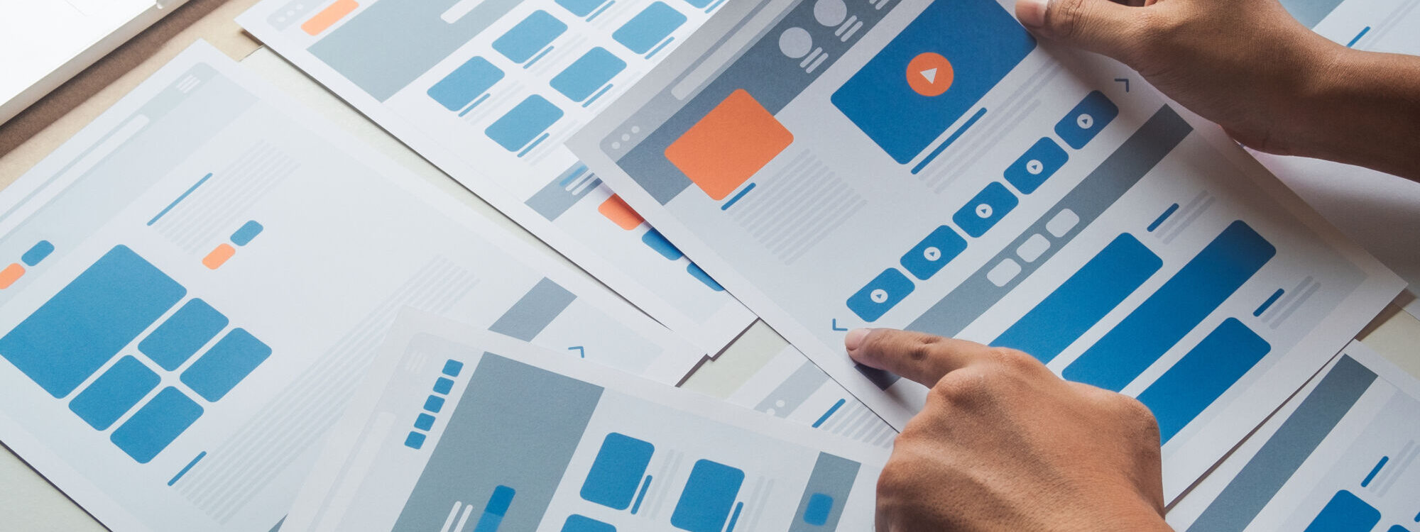 Mains examinant des échantillons de maquettes de conception web avec différentes dispositions de page.