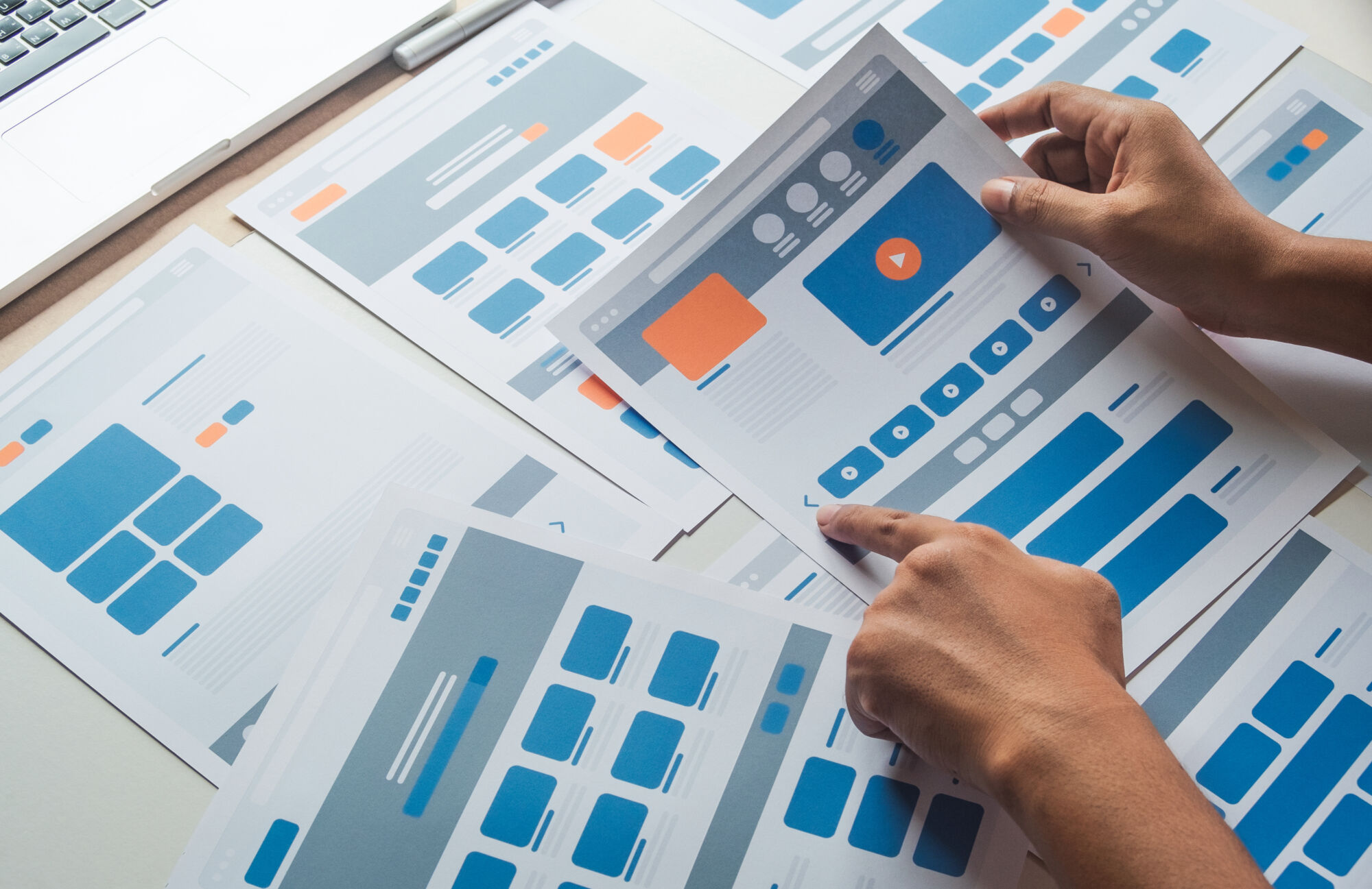 Mains examinant des échantillons de maquettes de conception web avec différentes dispositions de page.