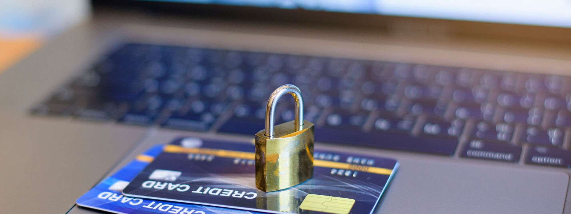 Carte de crédit sous un cadenas sur un clavier d'ordinateur, illustrant la sécurité des transactions en ligne.