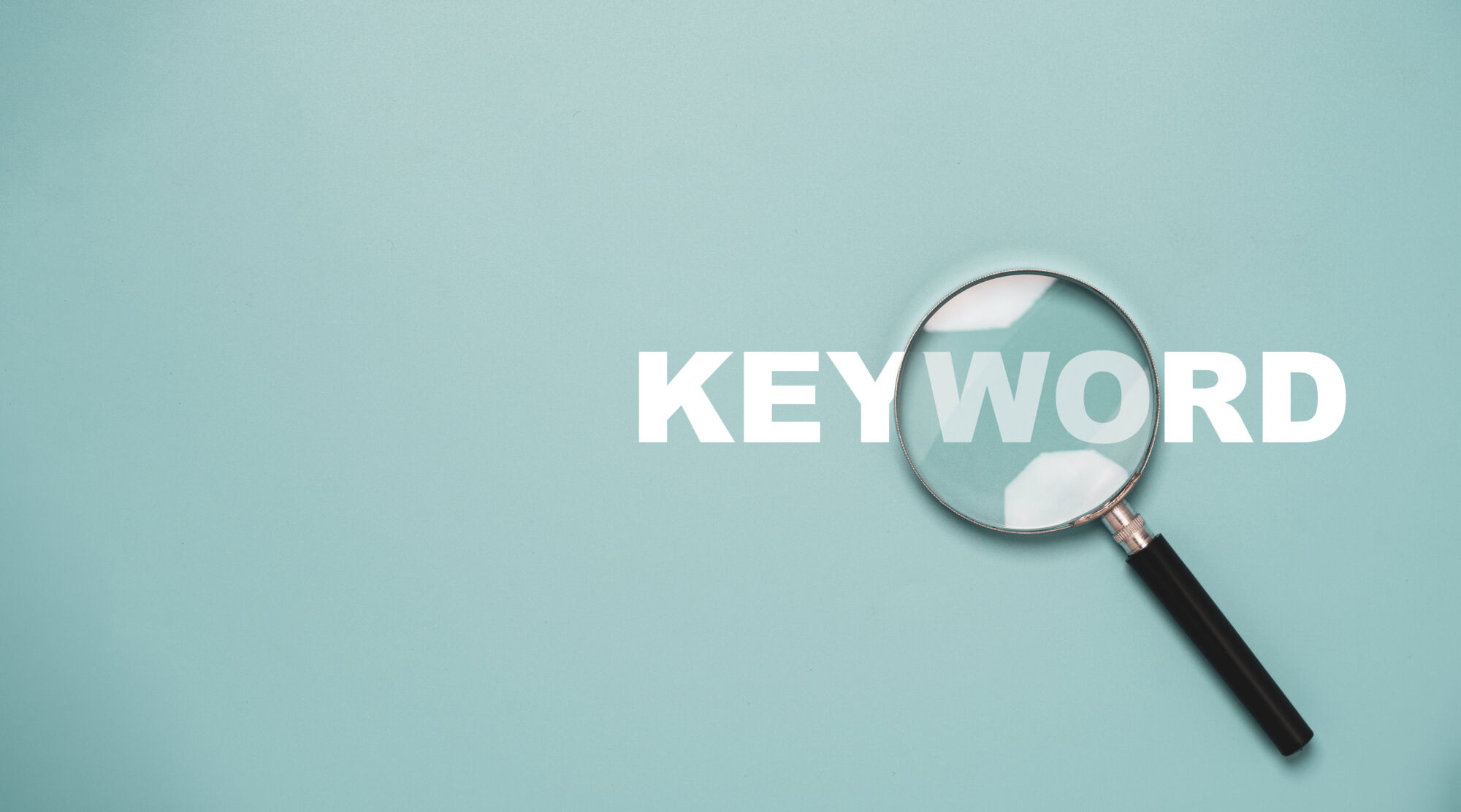 Loupe agrandissant le mot 'KEYWORD' sur un fond bleu uni pour le concept de recherche SEO.