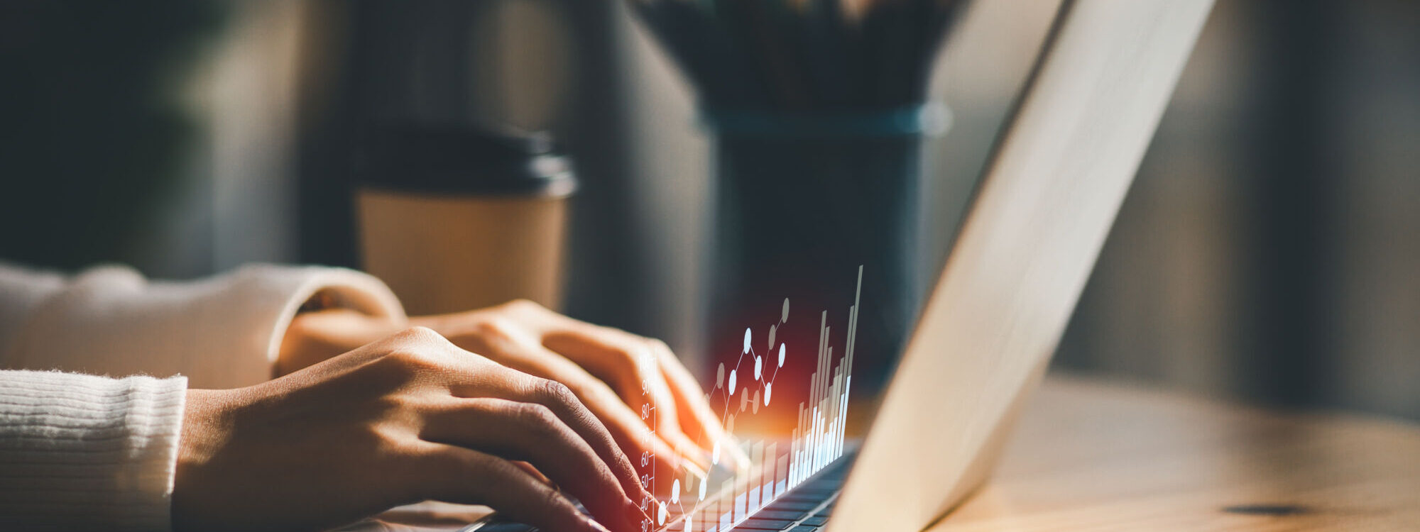 Mains tapant sur un clavier d'ordinateur portable avec des effets de lumière représentant l'activité numérique.