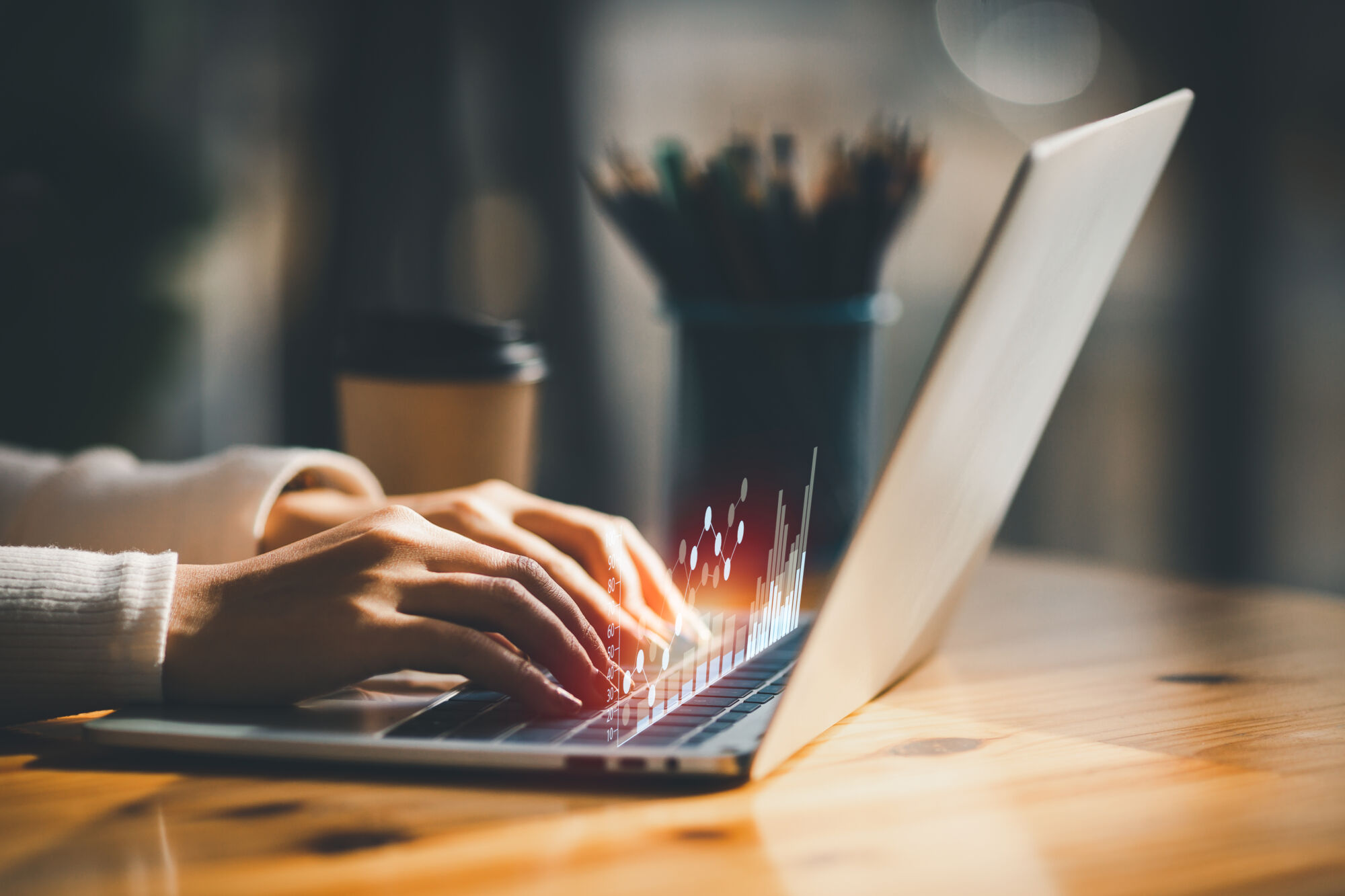 Mains tapant sur un clavier d'ordinateur portable avec des effets de lumière représentant l'activité numérique.