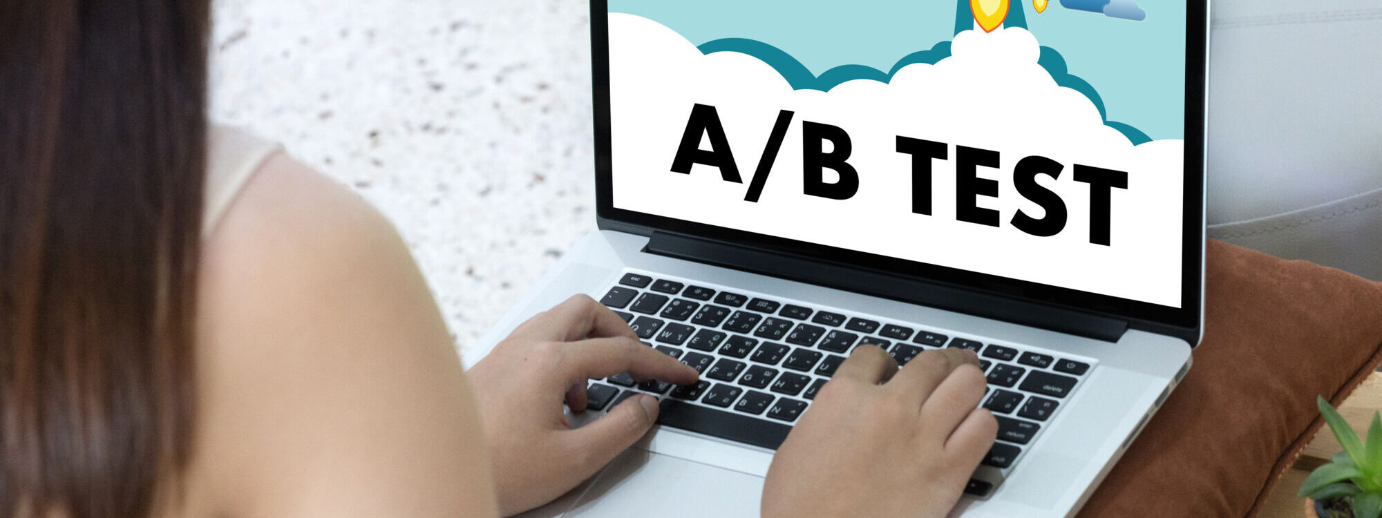 Femme travaillant sur un ordinateur portable affichant une illustration d'un test A/B avec une fusée décollant à travers les nuages.