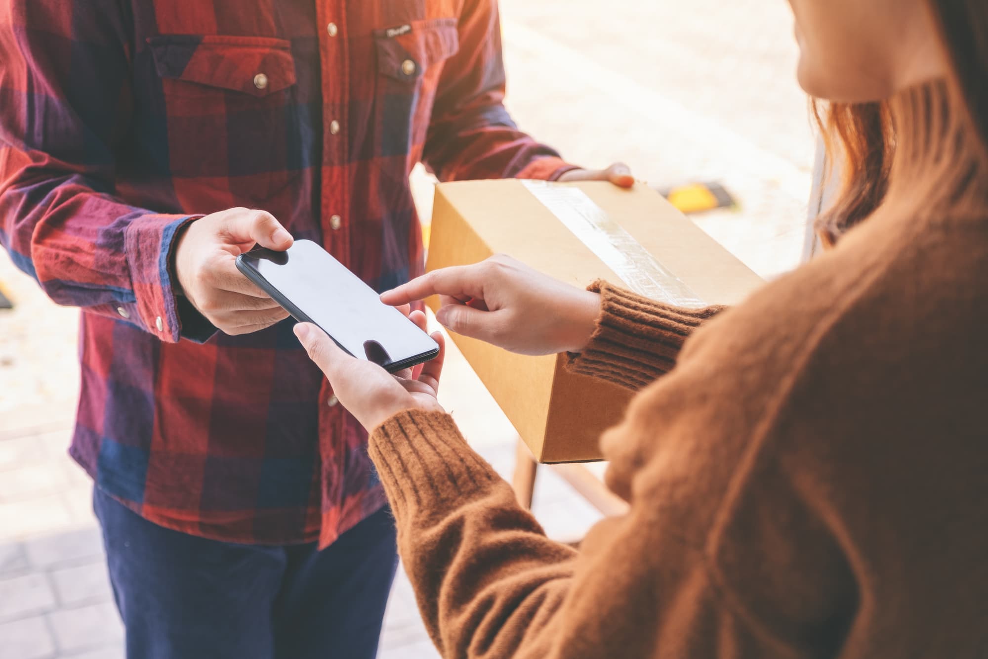 Echange entre deux personnes, signature sur un smartphone pour la livraison d'un colis.