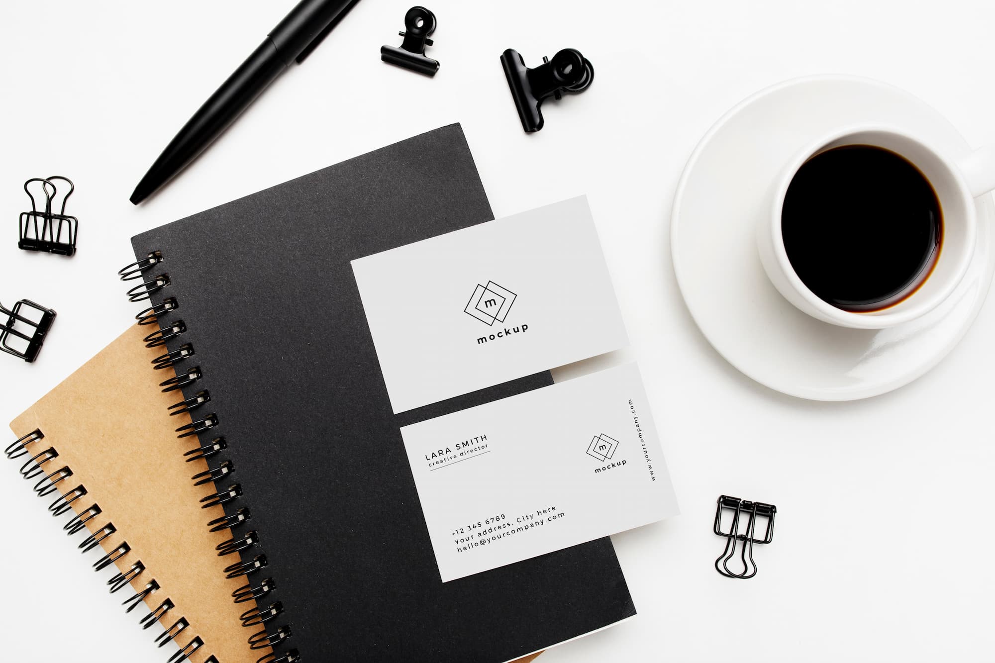 Carnets de notes, tasse de café et carte de visite avec maquette de logo sur un bureau blanc.