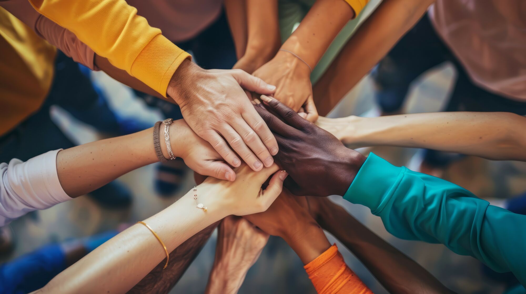 Groupe de personnes de diverses ethnicités superposant leurs mains en signe d'unité.