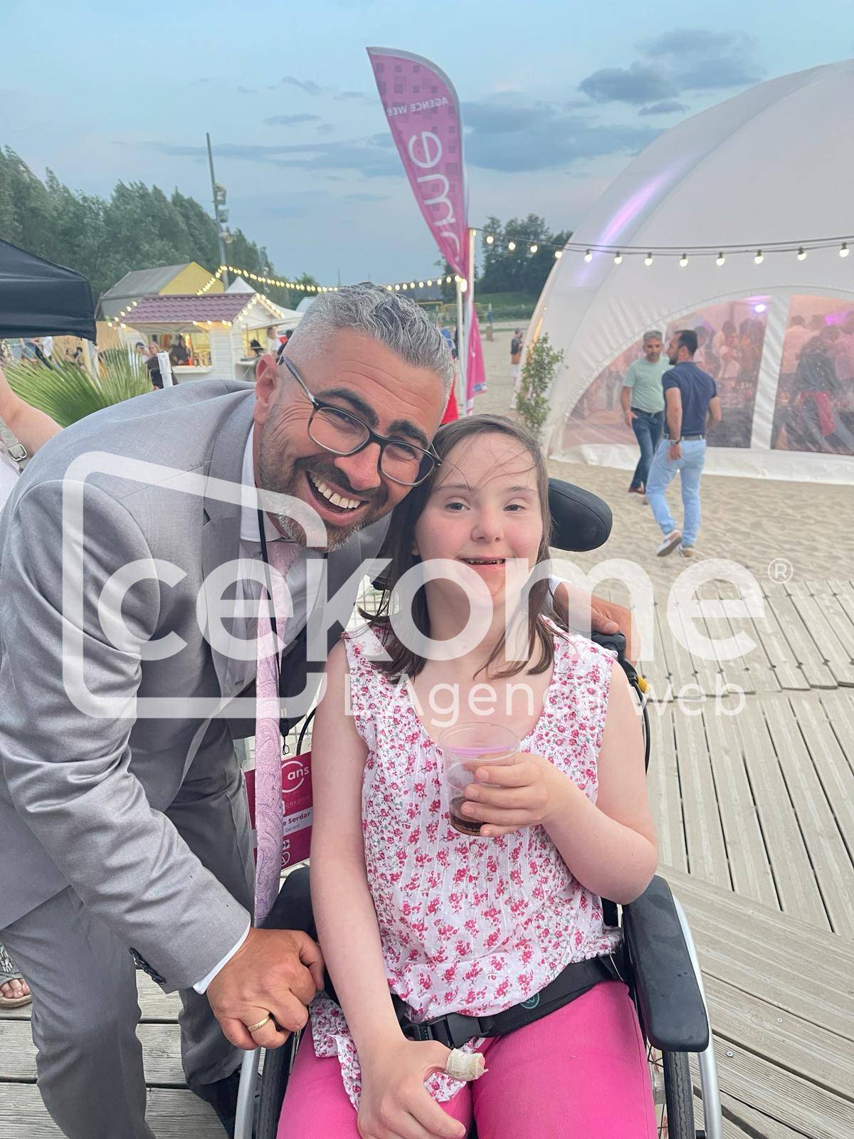 Homme souriant posant avec une jeune fille lors d'un événement de Cekome.