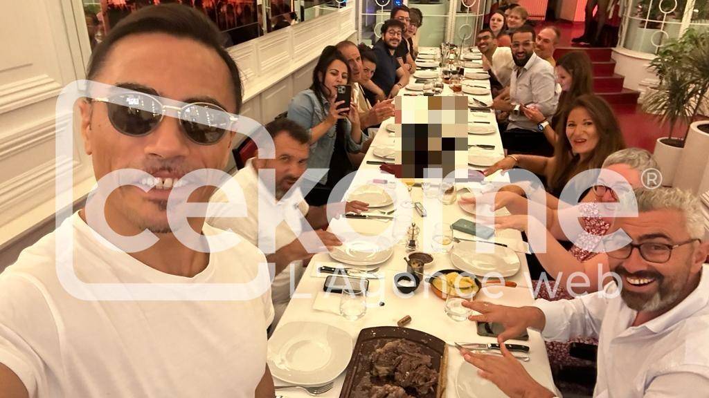 Selfie d'un homme avec un groupe de personnes attablées dans un restaurant.