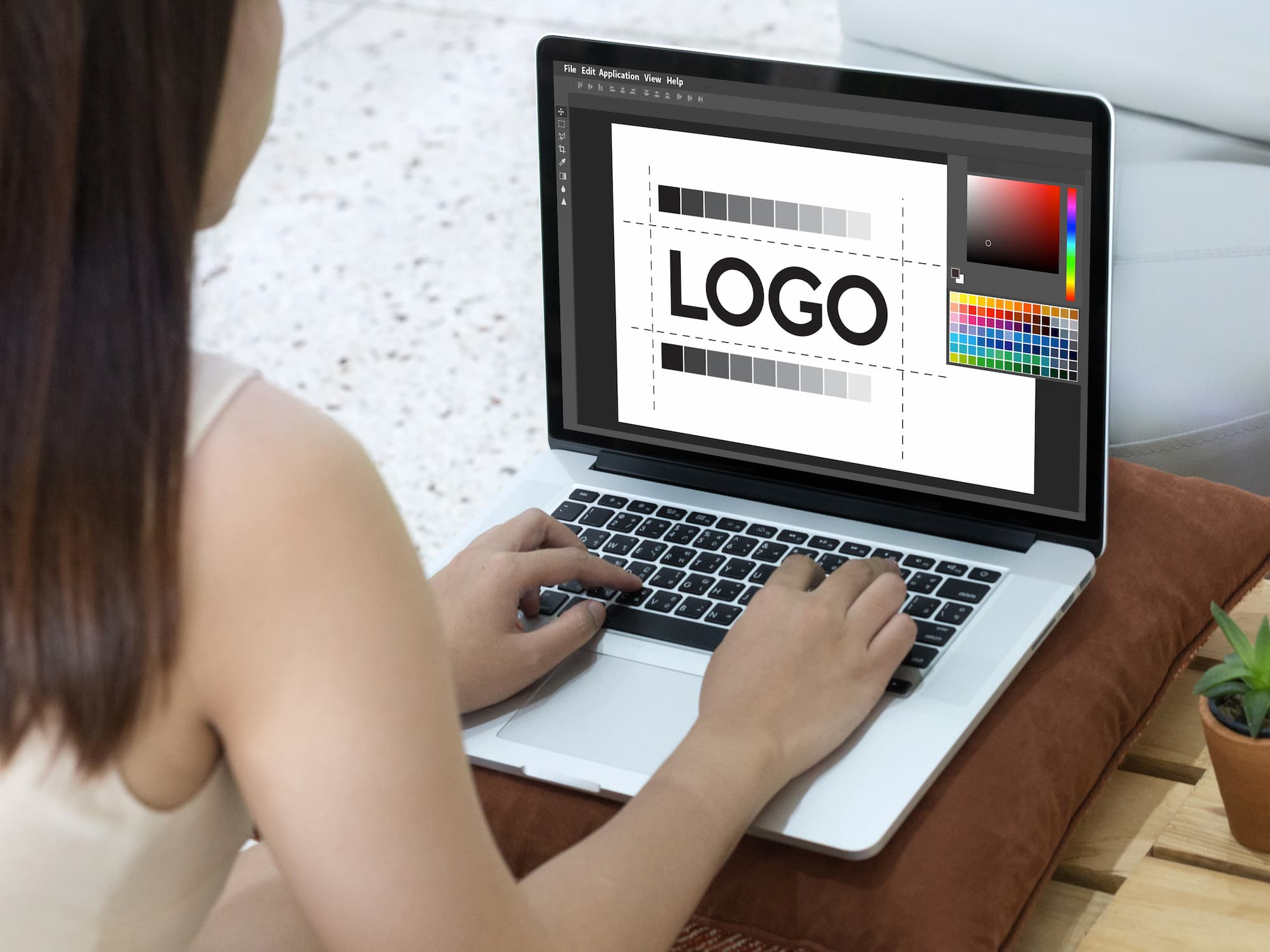 Designer graphique féminine retouchant un logo sur un ordinateur portable dans un bureau éclairé