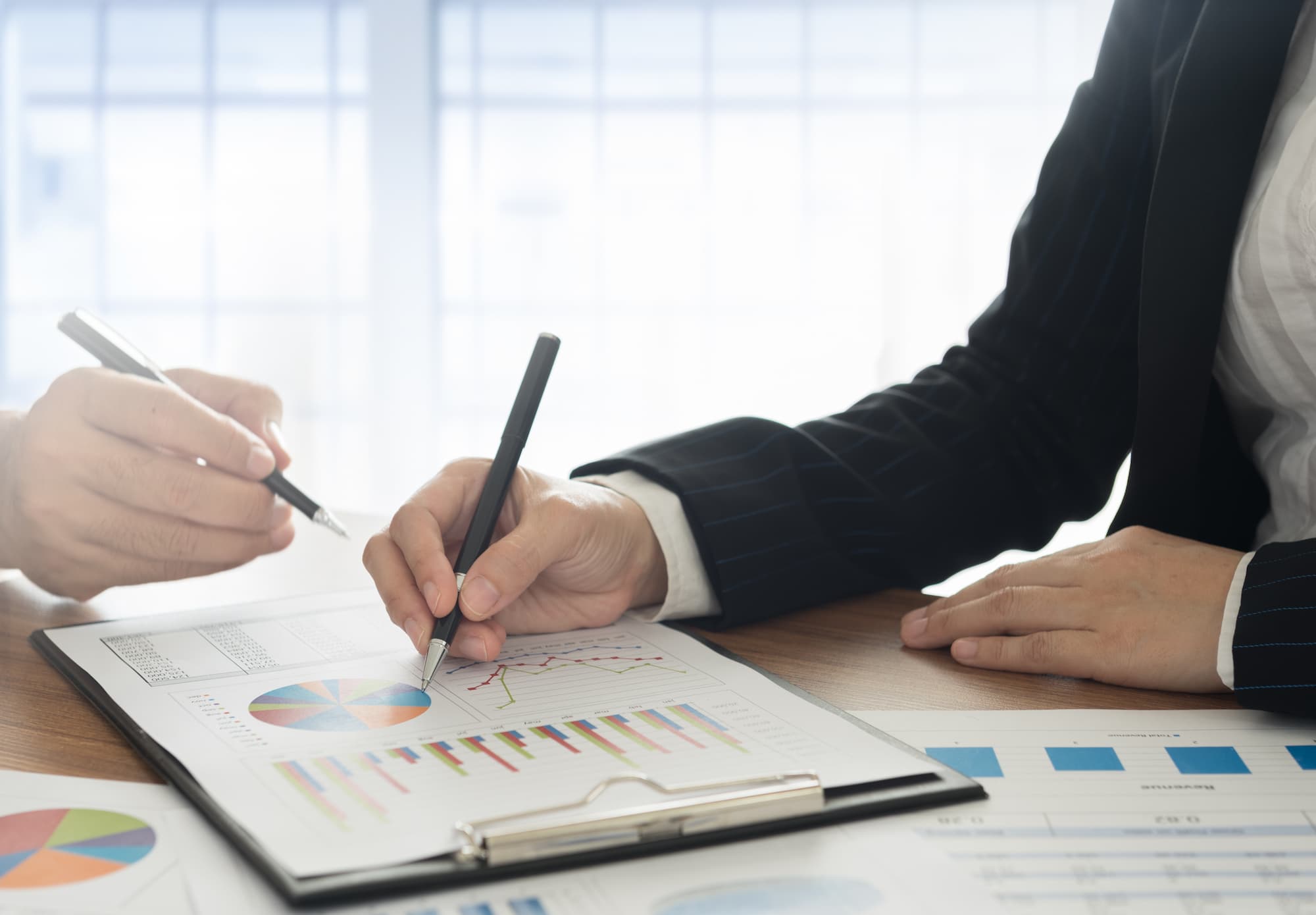 Deux collègues analysant des données financières sur des documents avec diagrammes circulaires.