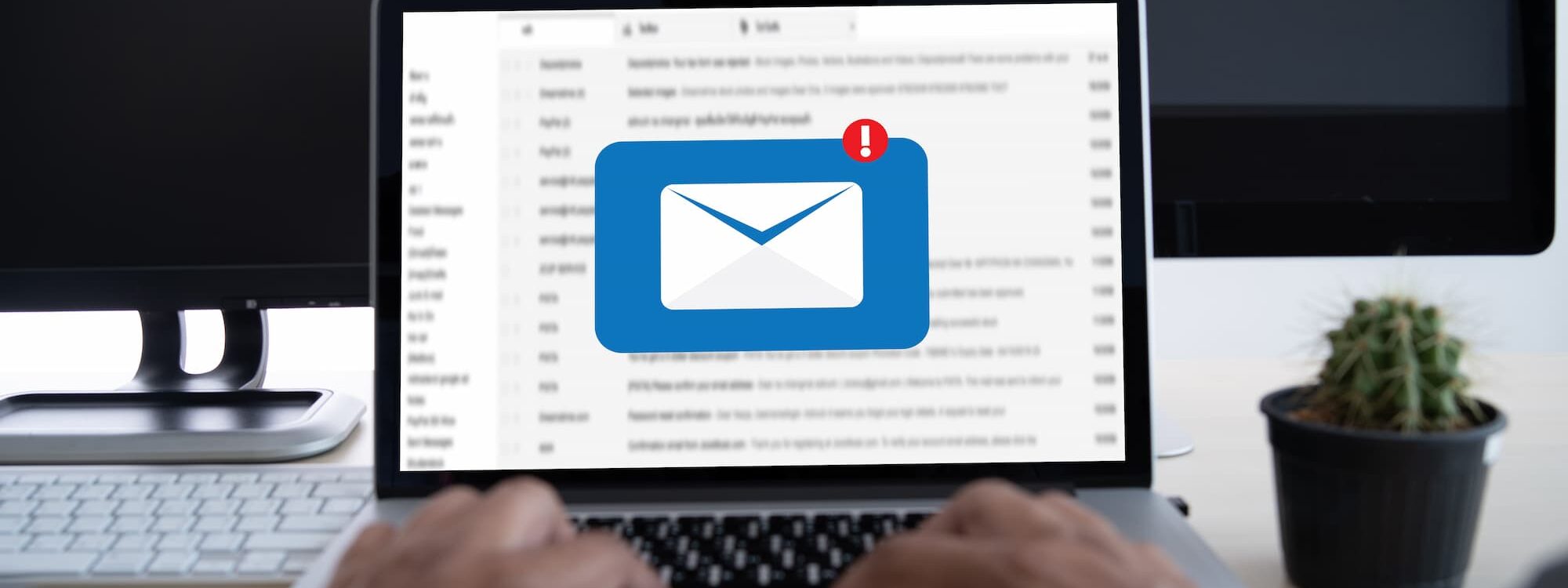 Vue en gros plan des mains d'une personne utilisant un ordinateur portable avec une notification d'email à l'écran.