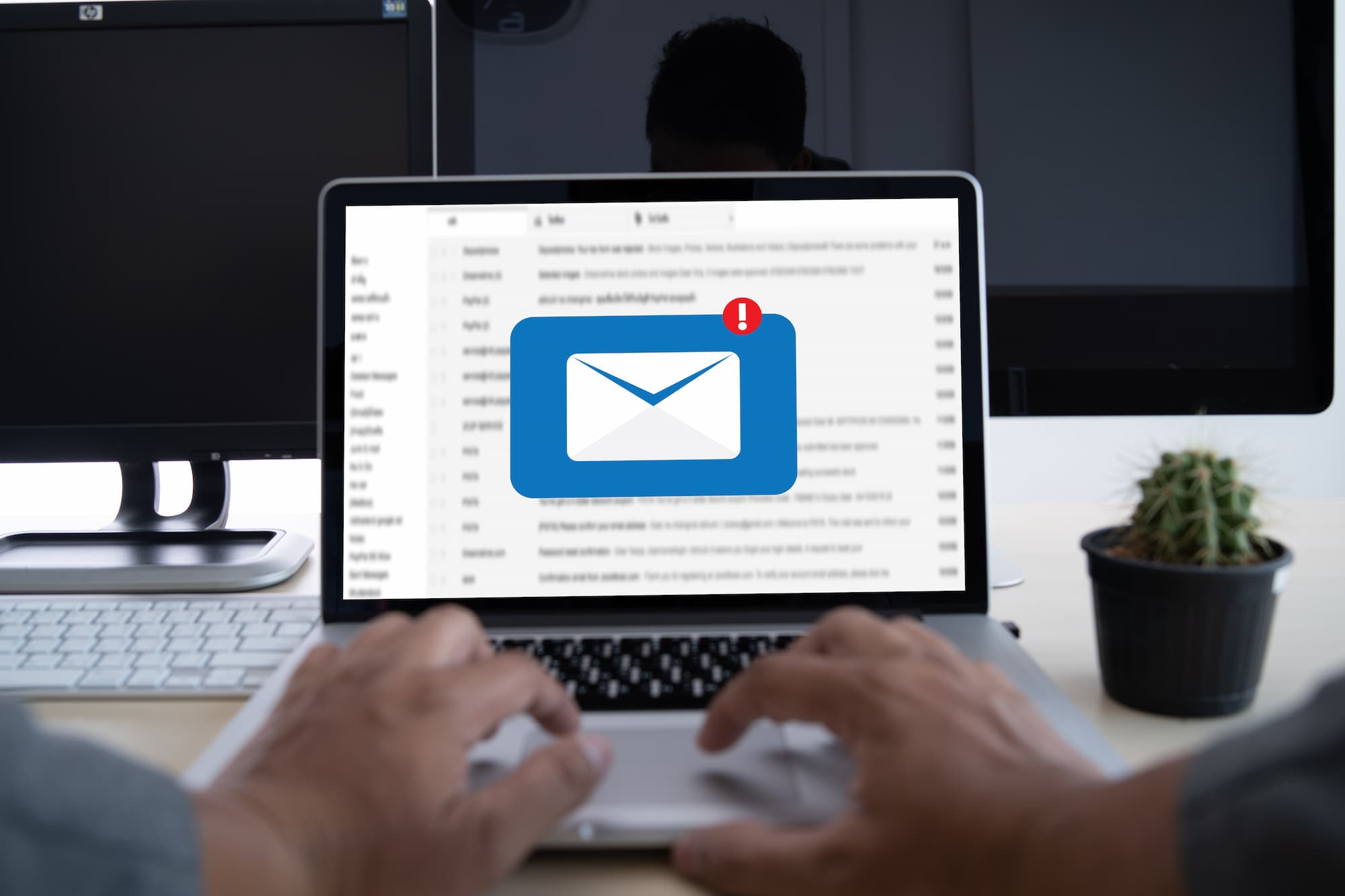 Vue en gros plan des mains d'une personne utilisant un ordinateur portable avec une notification d'email à l'écran.