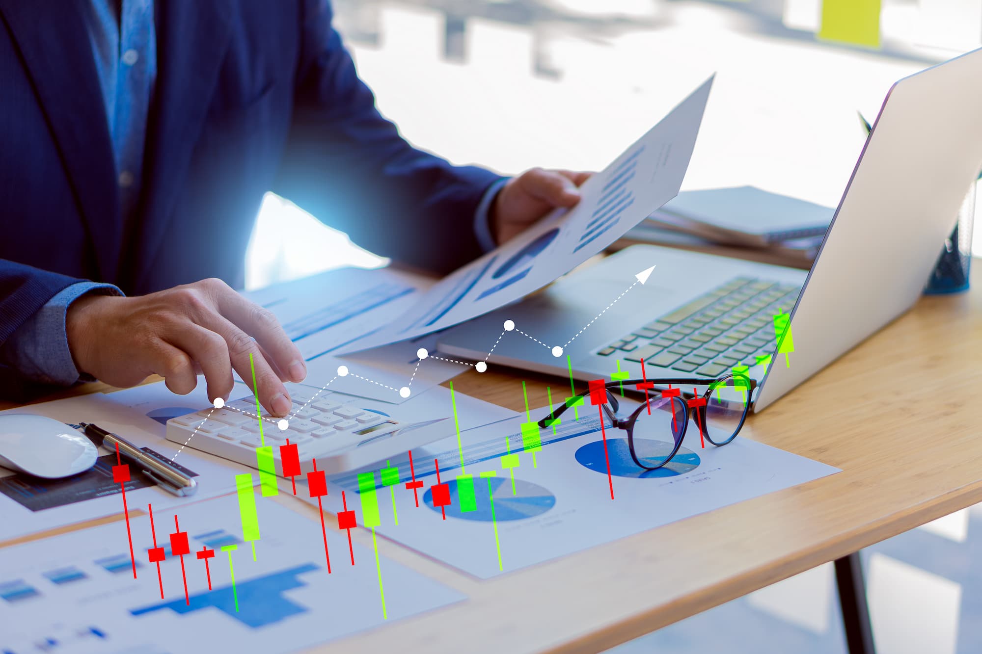 Analyse financière avec graphiques interactifs sur écran d'ordinateur et documents imprimés sur un bureau moderne.