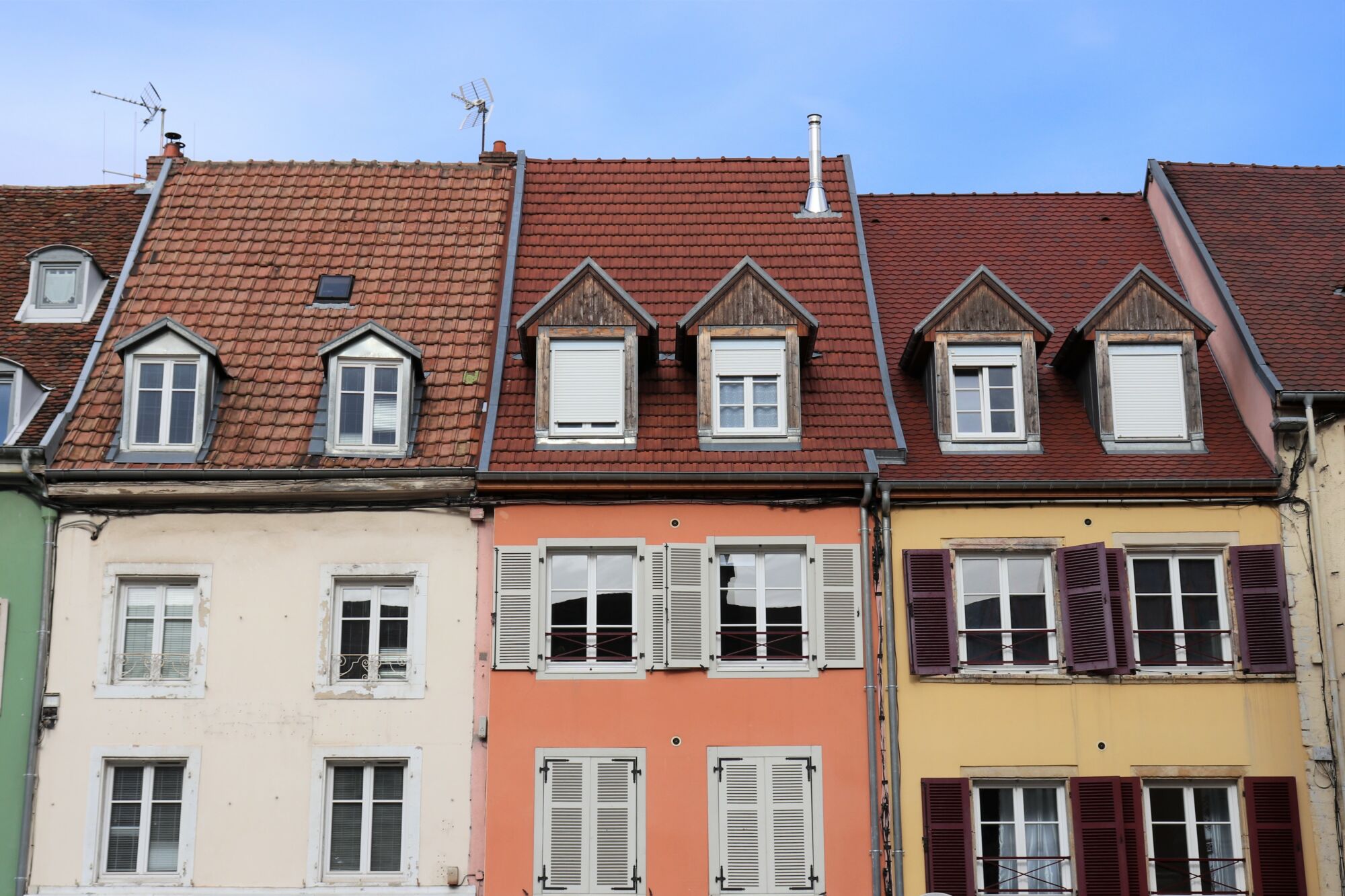 Façades colorées de maisons traditionnelles avec greniers et toits en tuiles.