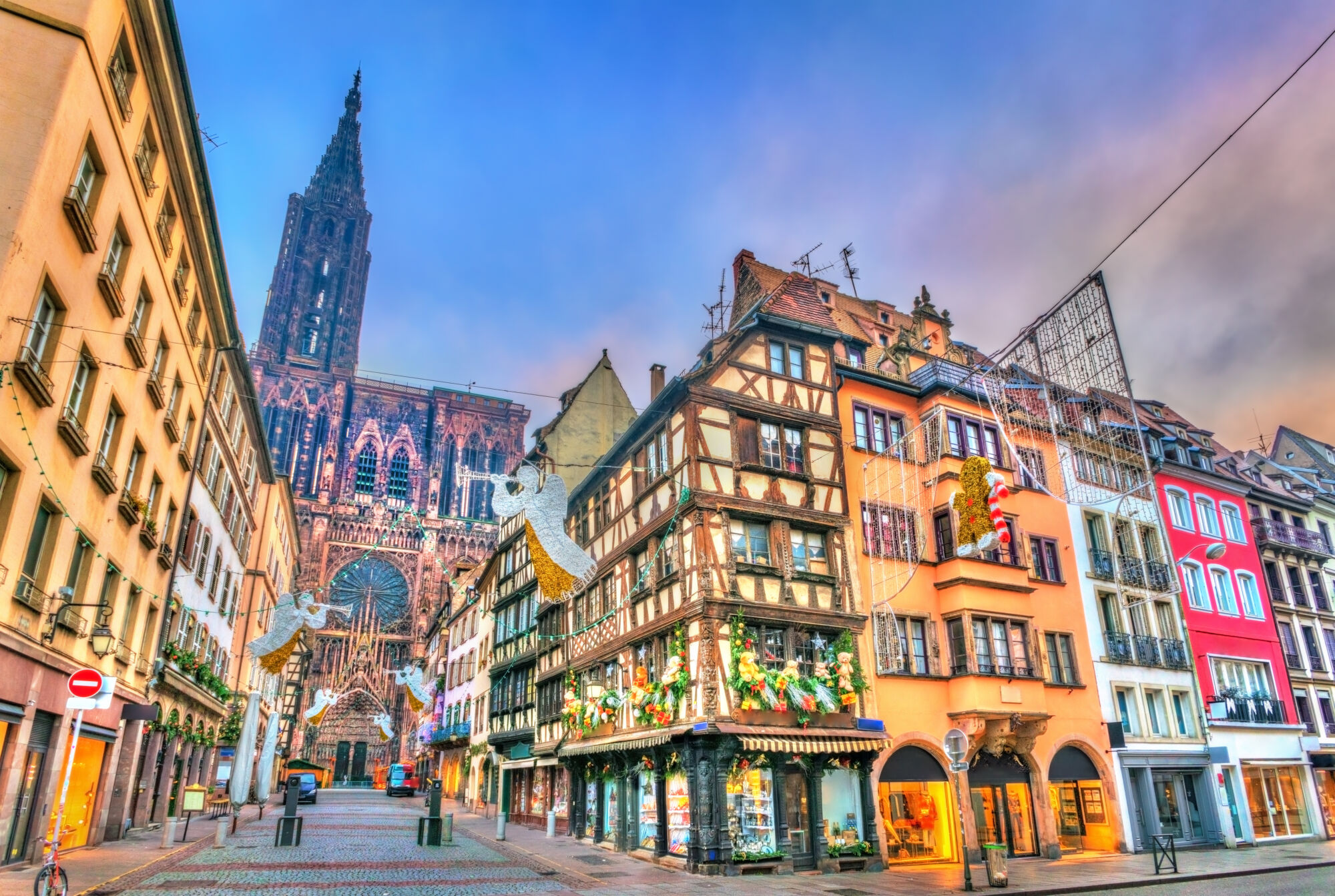 Rue pavée dans le centre historique avec maisons à colombages et grande cathédrale en arrière-plan.