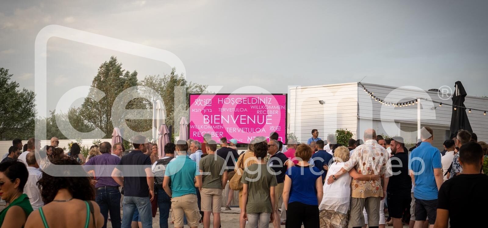 Participants devant un écran affichant 'Bienvenue' en plusieurs langues à un événement Cekome.