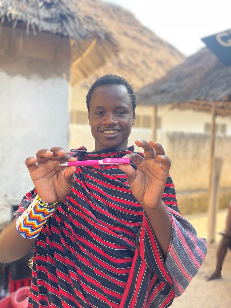 Jeune homme présentant un stylo rose avec sourire.