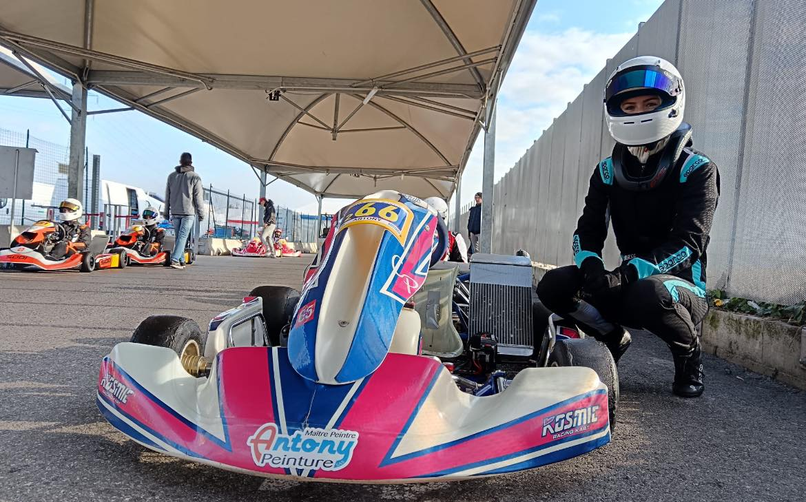 Pilote de karting se préparant avant la course, à côté de son véhicule sur la piste.