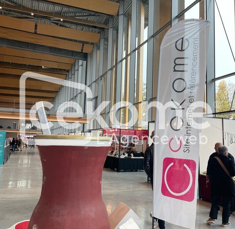 Stand de Cekome lors d'un salon professionnel avec un grand panneau et table haute.