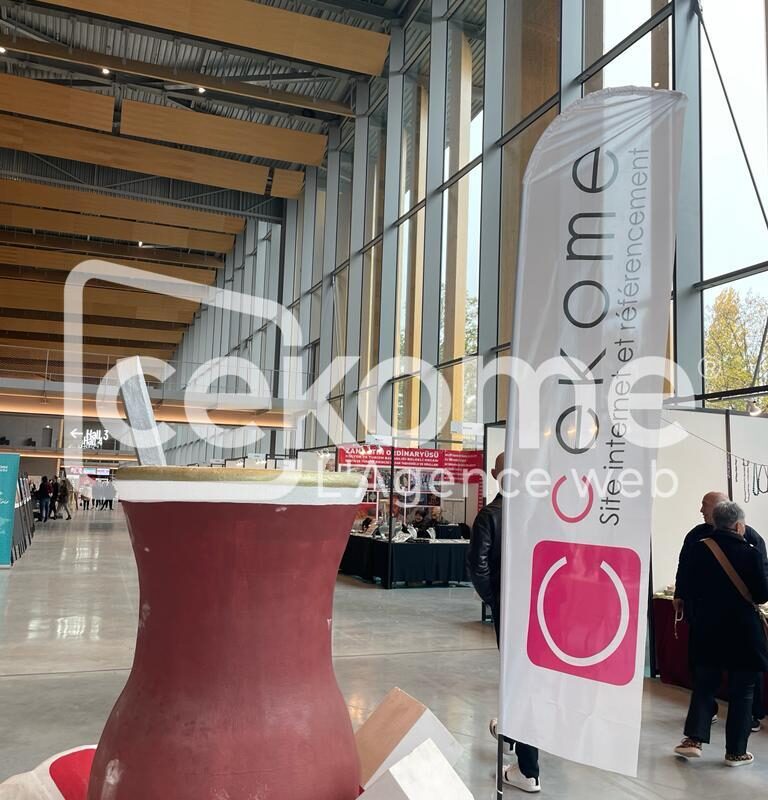 Stand de Cekome lors d'un salon professionnel avec un grand panneau et table haute.