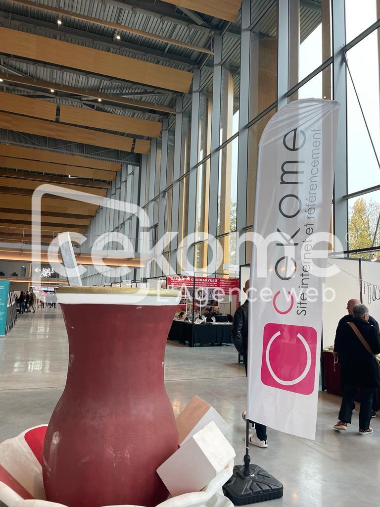 Stand de Cekome lors d'un salon professionnel avec un grand panneau et table haute.