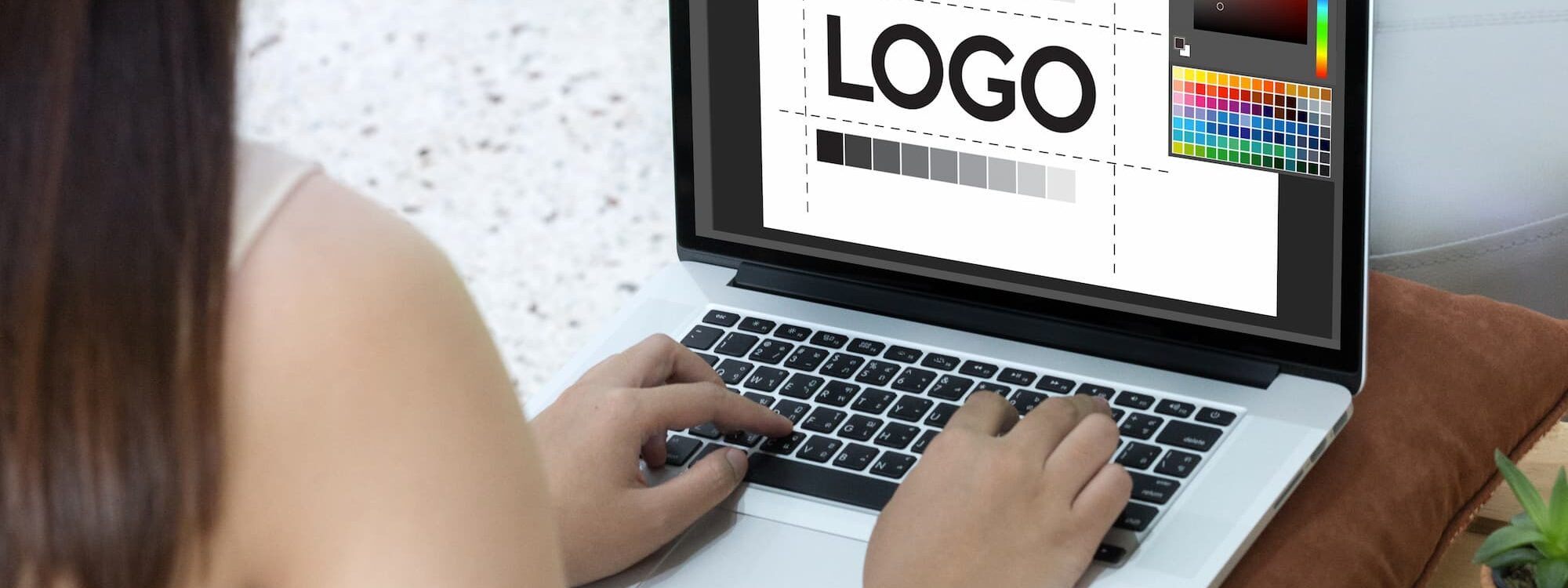 Designer graphique féminine retouchant un logo sur un ordinateur portable dans un bureau éclairé