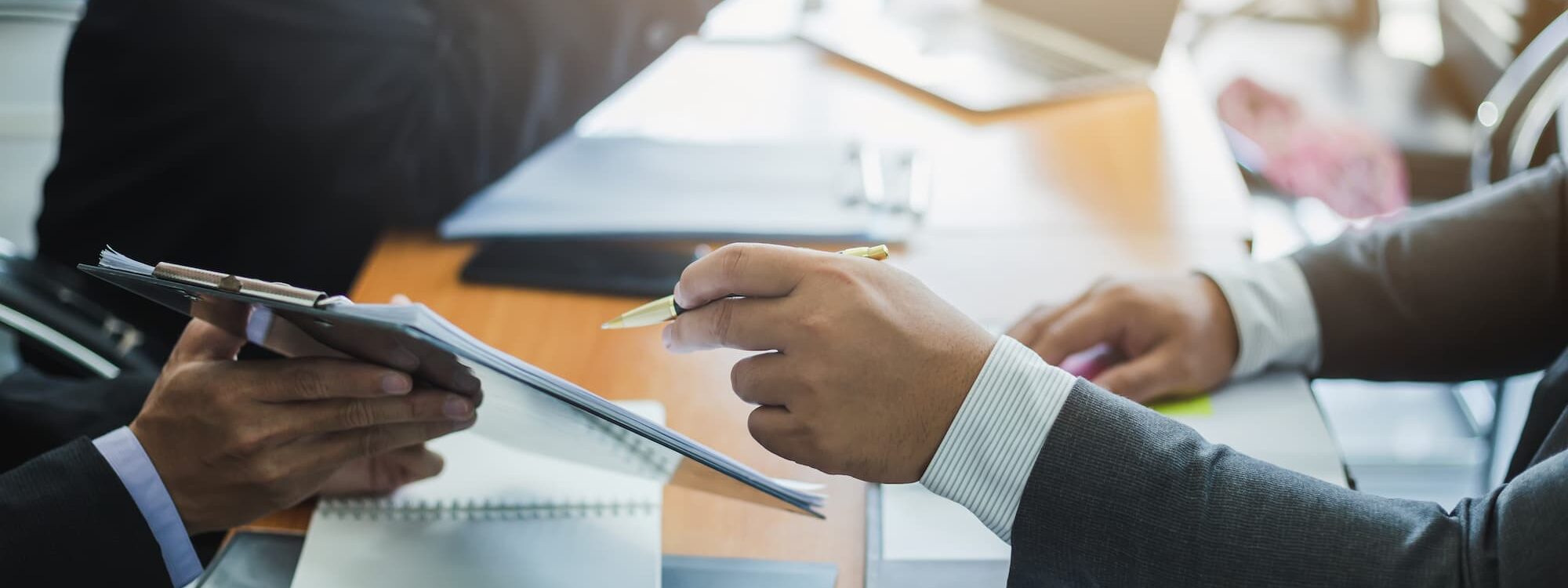 Deux professionnels en réunion avec ordinateur portable et documents financiers sur la table.