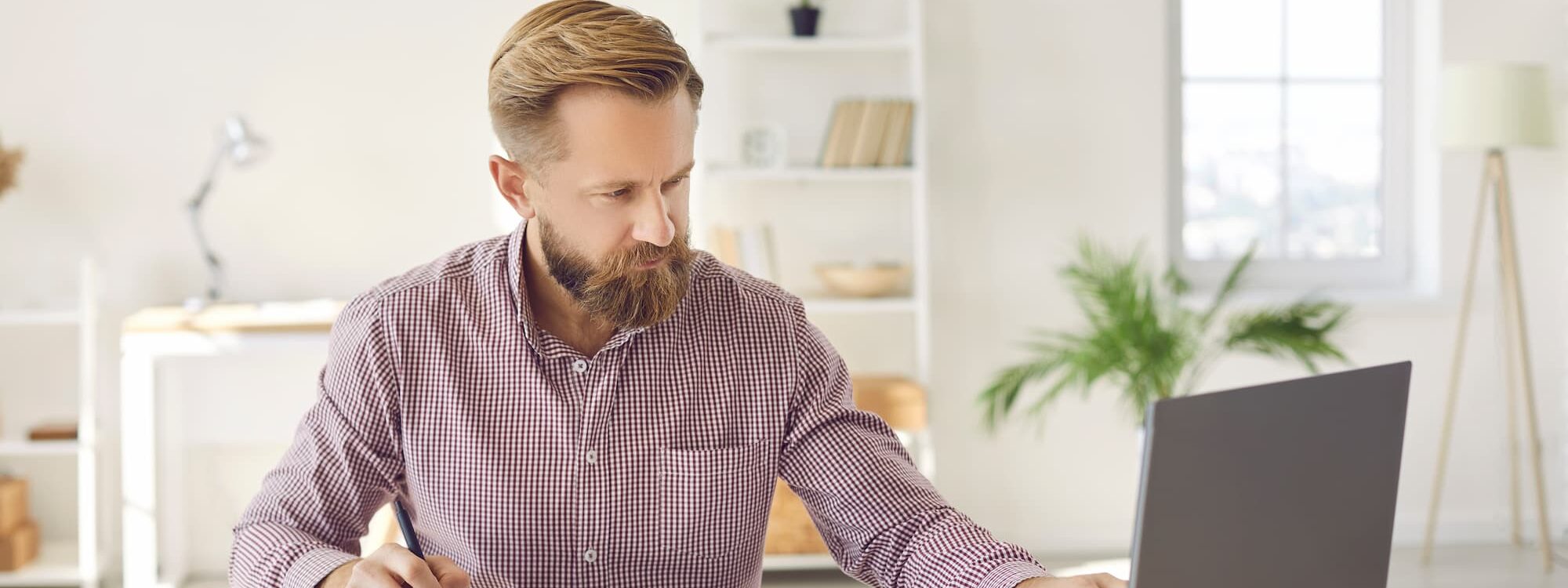 Homme d'affaires concentré travaillant sur ordinateur portable avec documents comptables et calculatrice sur son bureau.