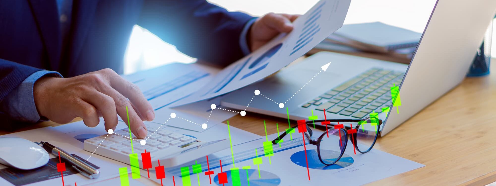 Analyse financière avec graphiques interactifs sur écran d'ordinateur et documents imprimés sur un bureau moderne.