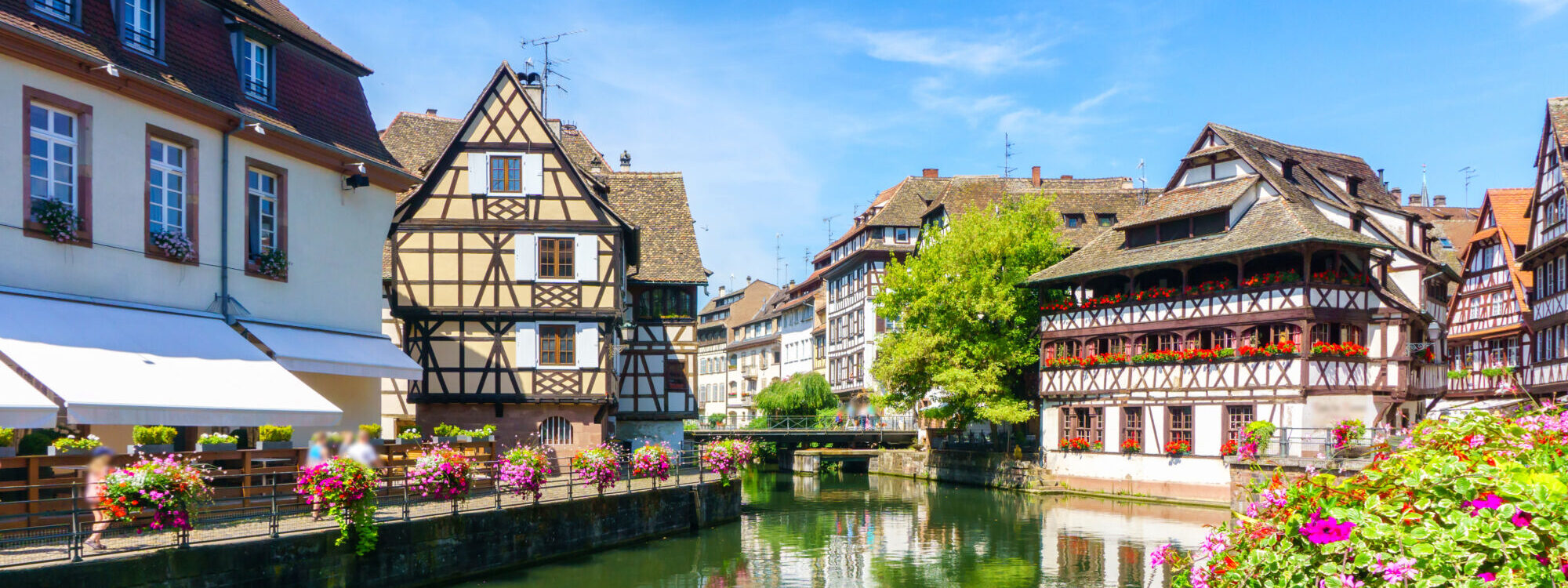 Architecture traditionnelle avec des maisons à colombages le long d'un canal en journée ensoleillée.