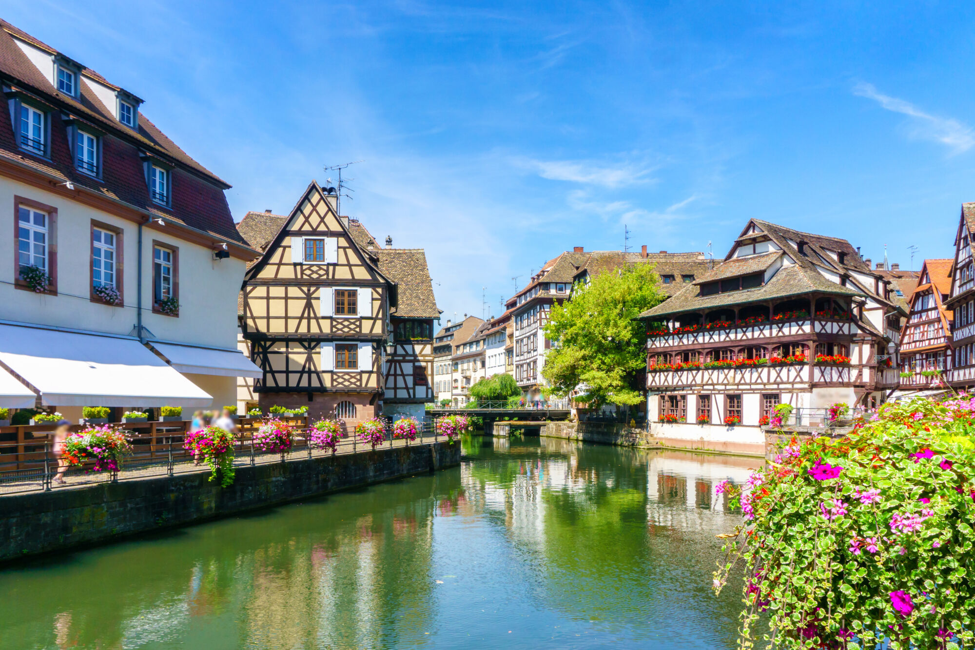 Architecture traditionnelle avec des maisons à colombages le long d'un canal en journée ensoleillée.