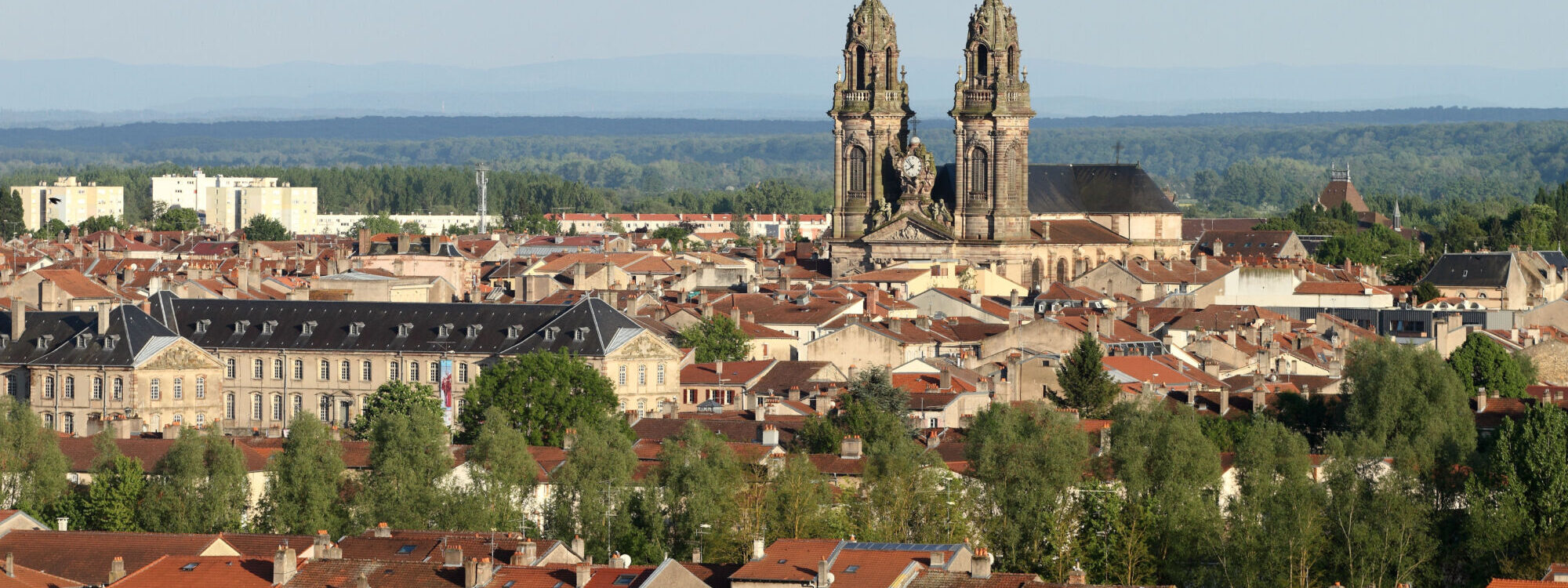 Vue panoramique sur une ville avec une cathédrale à deux clochers dominant les toits.