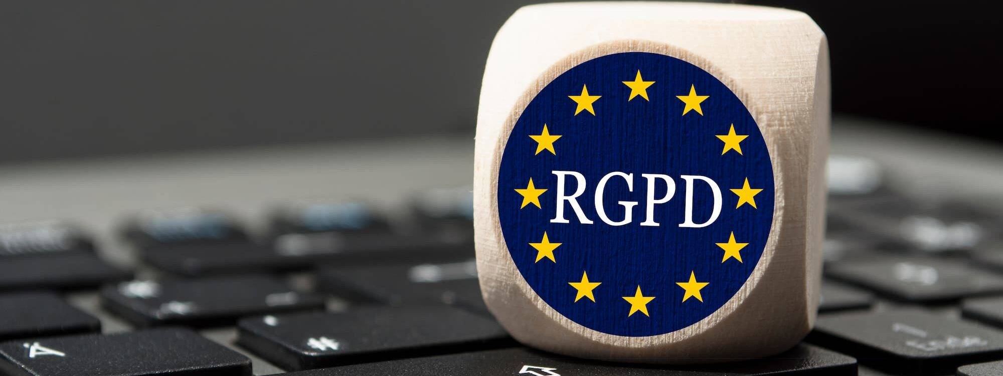 Dé déposé sur un clavier d'ordinateur avec le symbole RGPD pour représenter la conformité à la réglementation européenne.